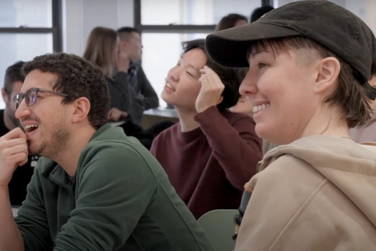 People in an office or classroom smiling at what they are looking at.