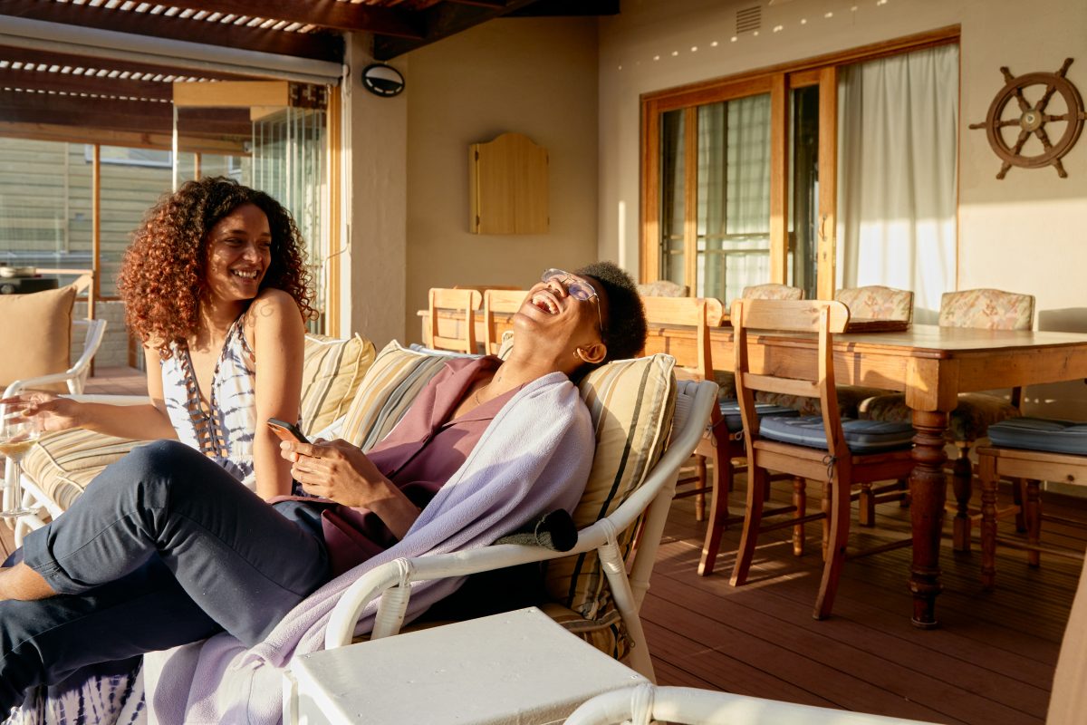 A man and a woman laughing on a couch in a vacation rental.