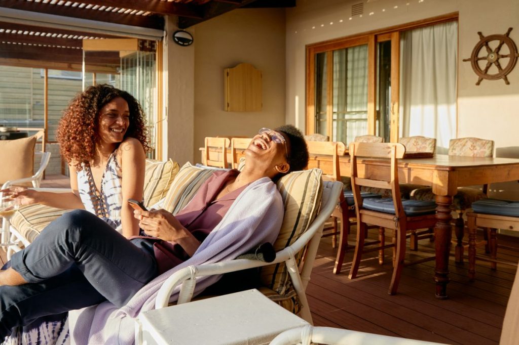 A man and a woman laughing on a couch in a vacation rental.