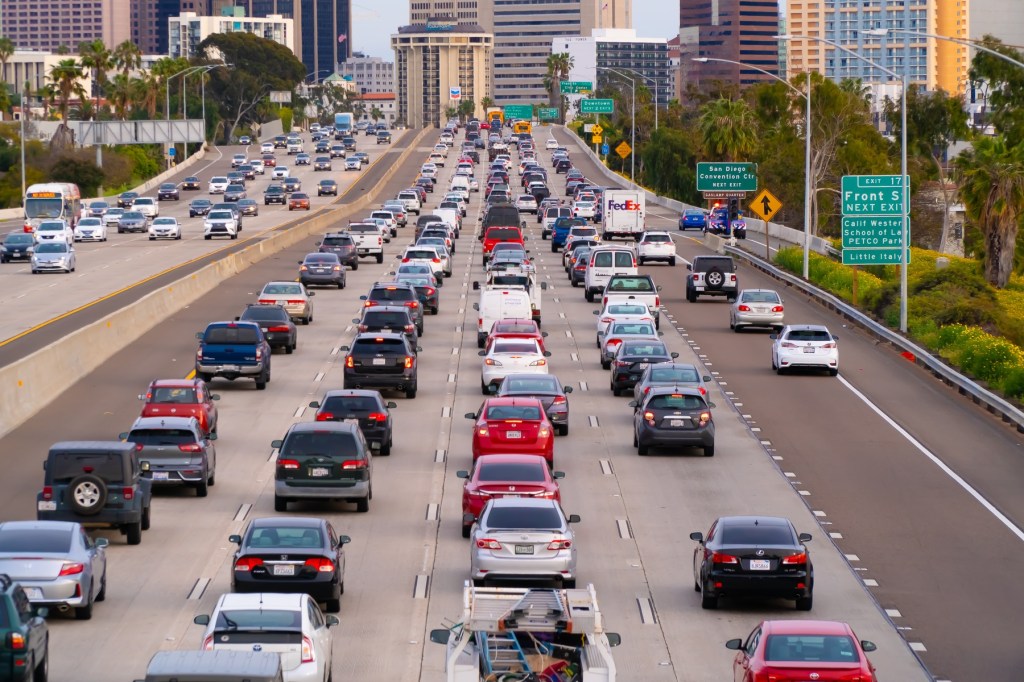 Multiple lanes of traffic with a city skyline in the distance.