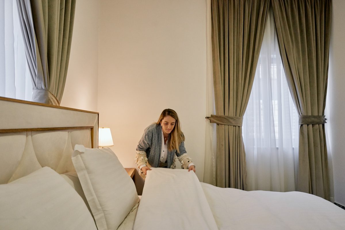 A woman making a bed in an Airbnb in Amman, Jordan.