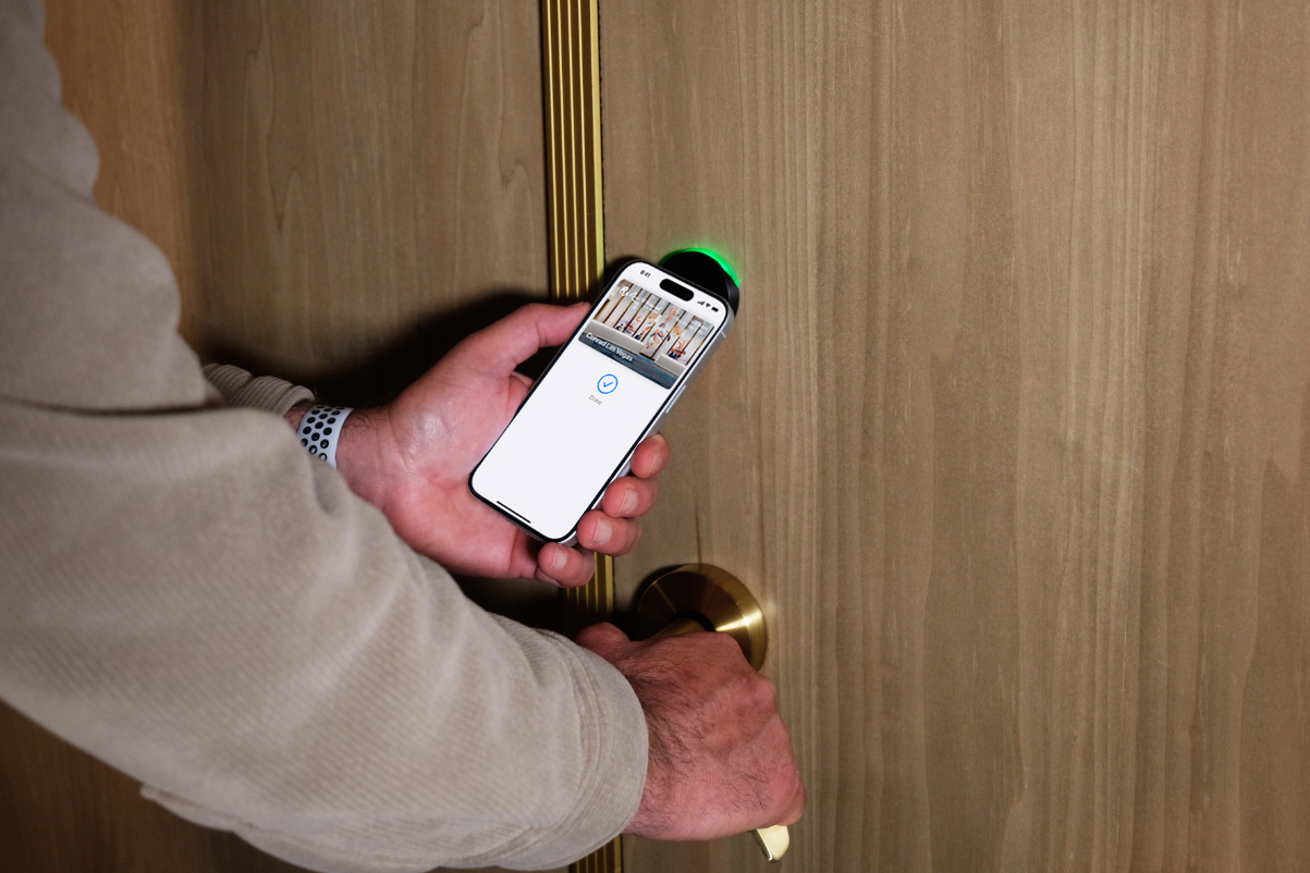 view of a man holding a phone to open a door at a hotel