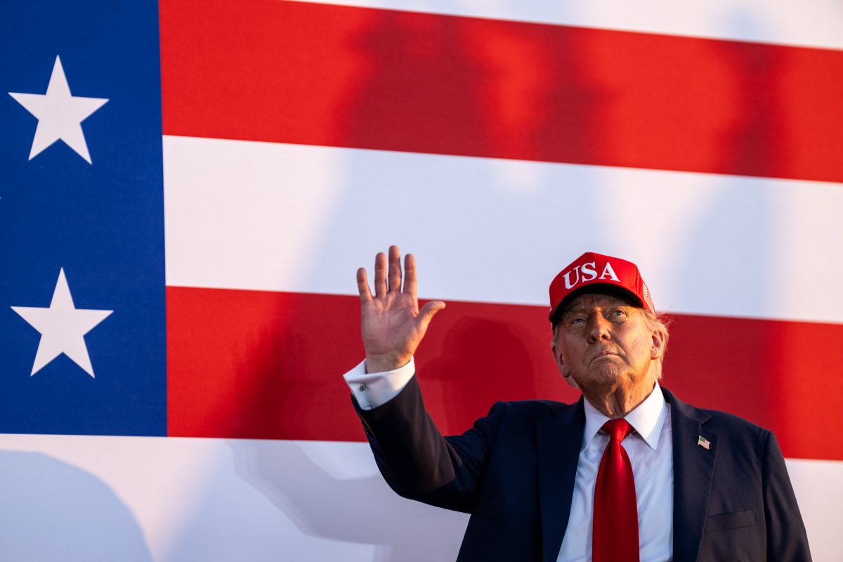 President Donald Trump wearing a USA hat with a U.S. flag.