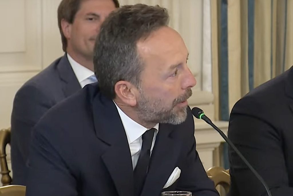 A man in a suit speaking into a microphone at the White House.