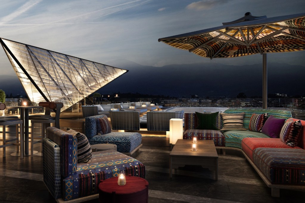 View of the rooftop bar at the Hilton Kathmandu Hotel with couches with distinctive textile patterns and a sunset