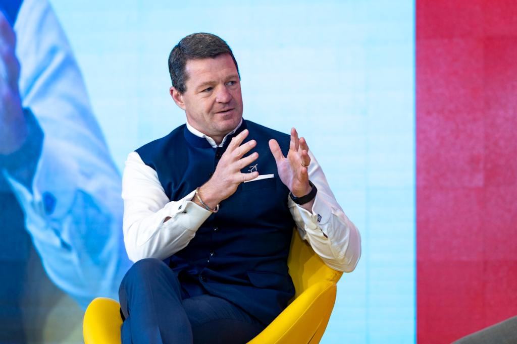 A man on stage gesturing with his hands as he speaks.
