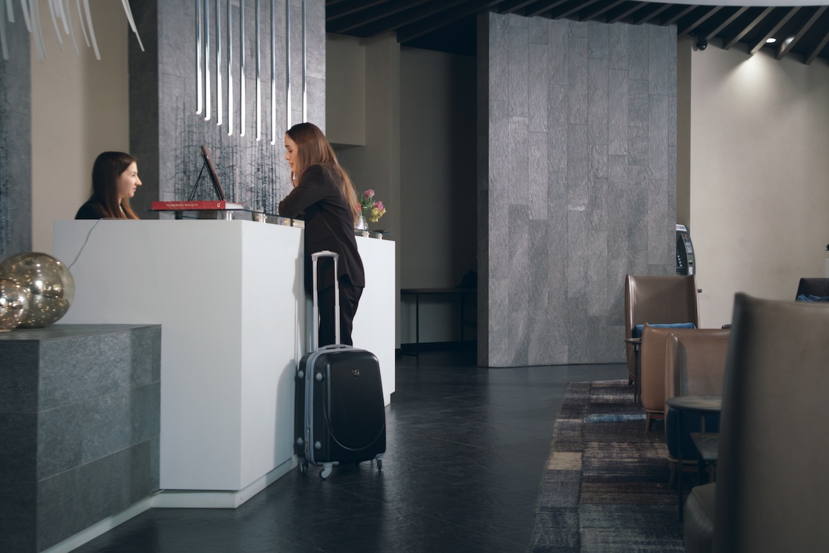 Business woman with travel suitcase arriving in hotel at vacation