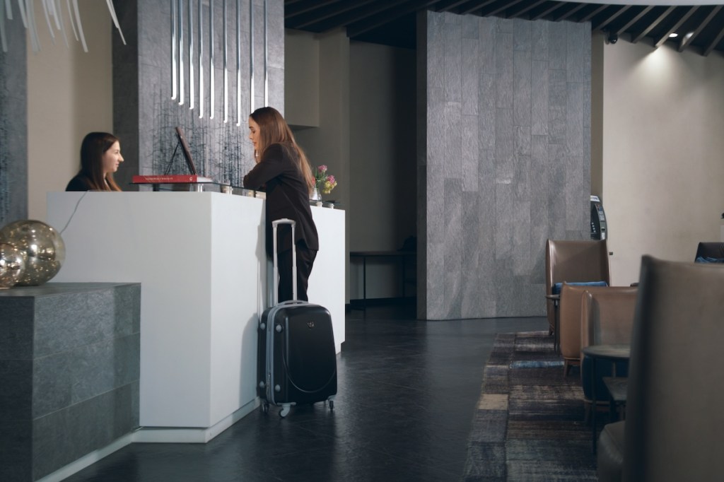 Business woman with travel suitcase arriving in hotel at vacation