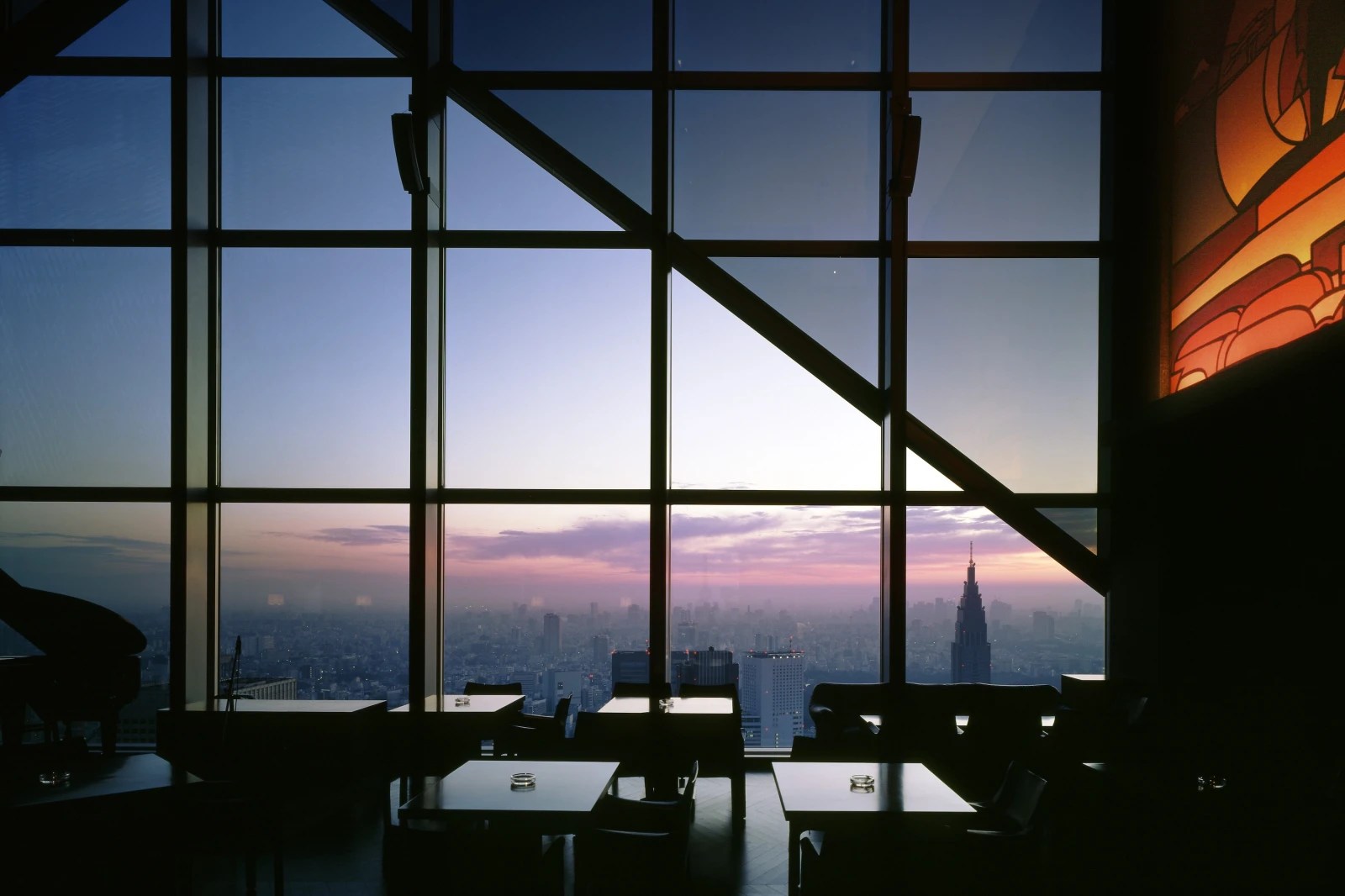 View of the Tokyo skyline from the New York Grill and Bar at the Park Hyatt Hotel. It's reopening in December 2025, seen at sunset.