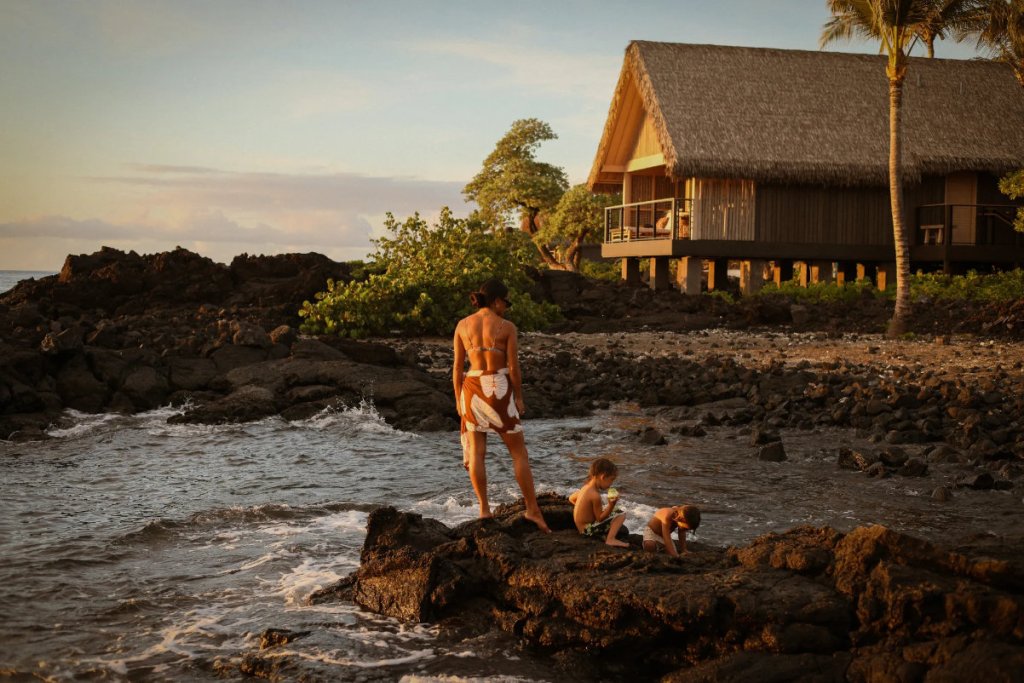 image from a Rosewood Hotels and Resorts brand campaign of a woman with children on a beautiful shorefront
