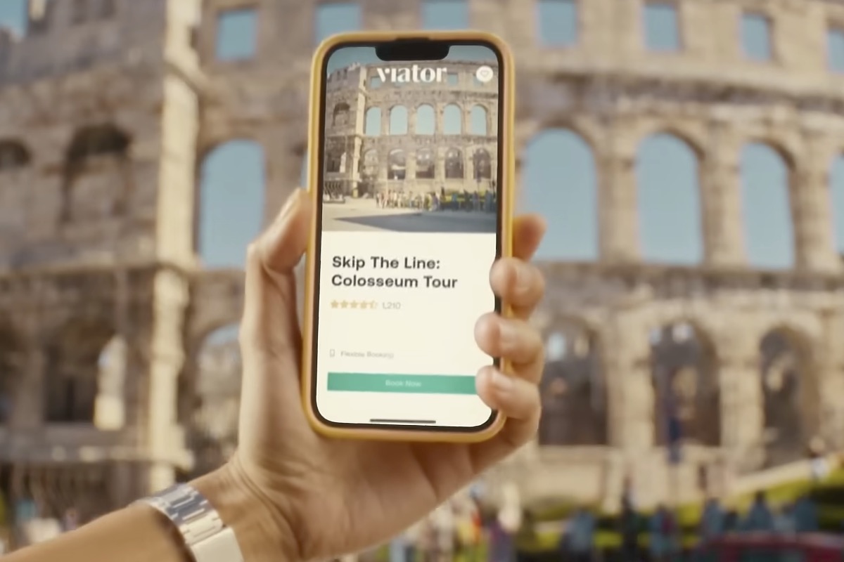 Someone's holding the Viator app on a phone and in the background is the Colosseum.