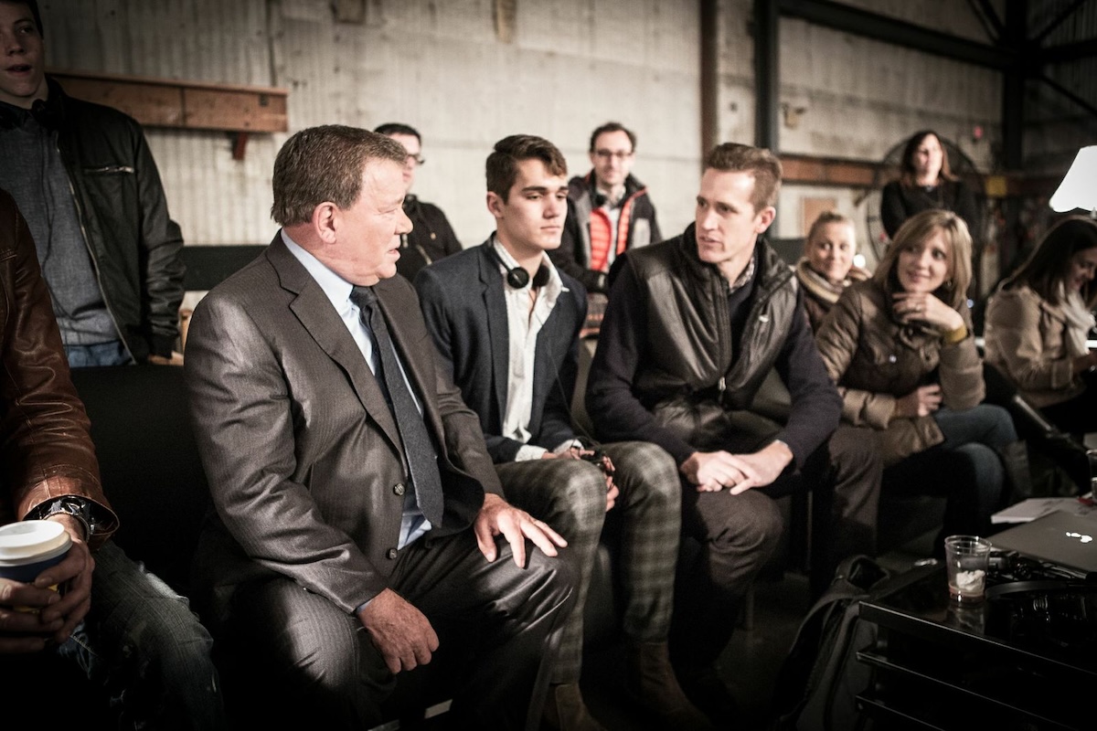 People, including actor William Shatner, sitting on stage at an event to mark the 20th anniversary of Priceline