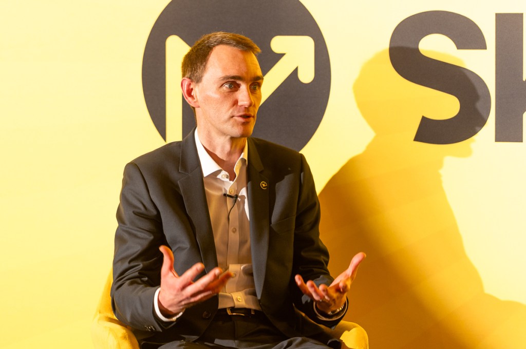 Image of a French male executive speaking on stage at an event in London.