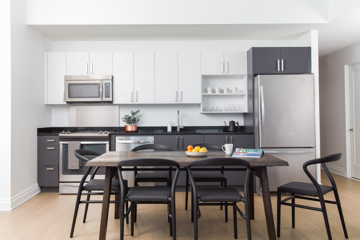 An image of a kitchen in a two-bedroom unit at 70 Pine Street in Manhattan that is managed by Kasa, which runs hotel-style lodgings in residential buildings and hotels. It's a brightly lit room with modern kitchen appliances and furniture.