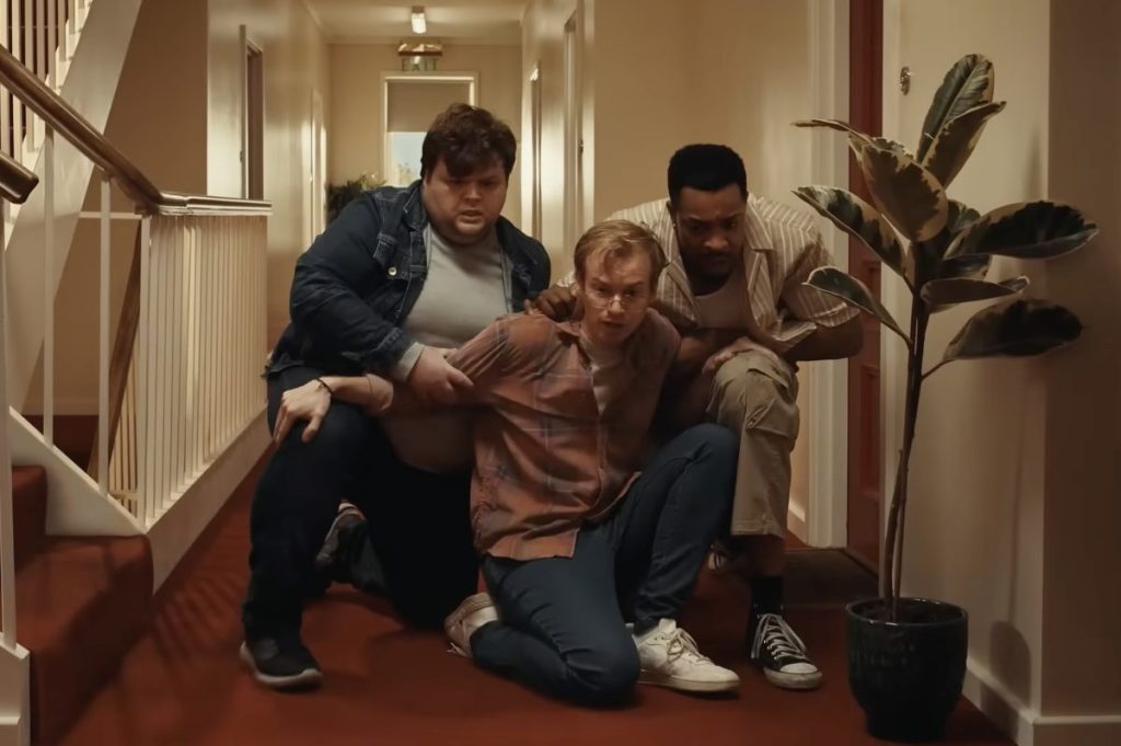 3 young people inside a home clutching one another and looking fearful in a humorous advertisement