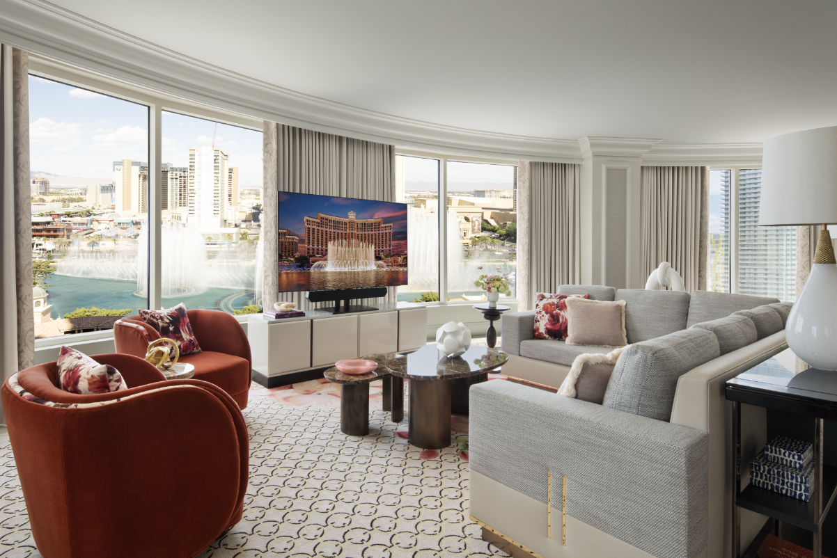 Image of a two-bedroom suite with a view of the Bellagio fountains in Las Vegas, with sunlight streaming in. Nice furniture.
