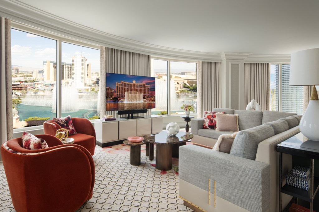 Image of a two-bedroom suite with a view of the Bellagio fountains in Las Vegas, with sunlight streaming in. Nice furniture.