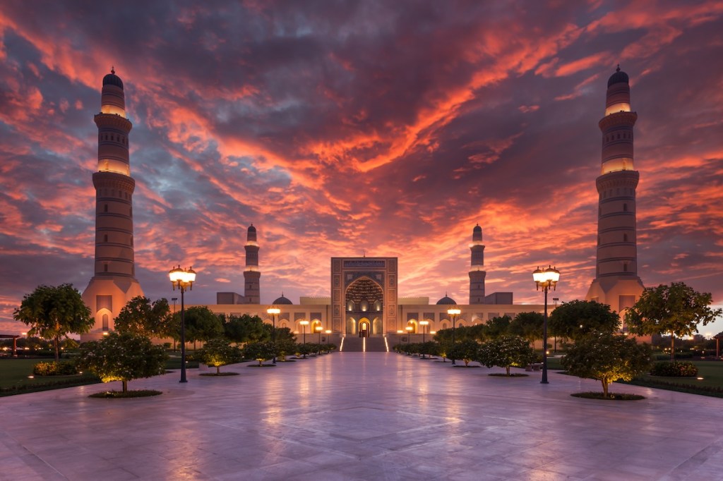 sunset view of a grand mosque and turrets.