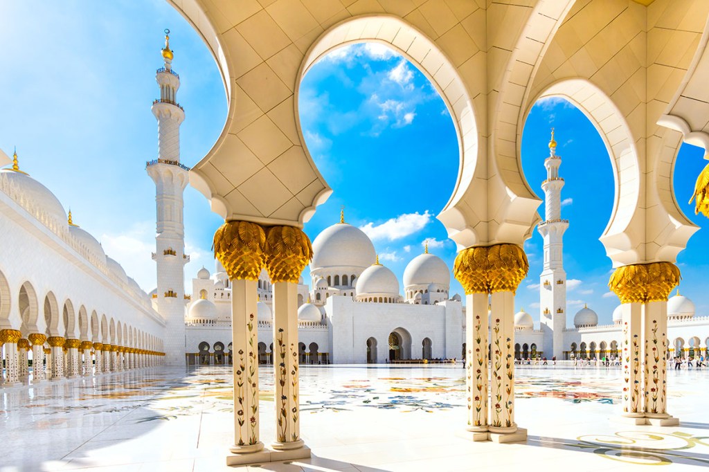 courtyard of a white marble-covered mosque in the sunlight