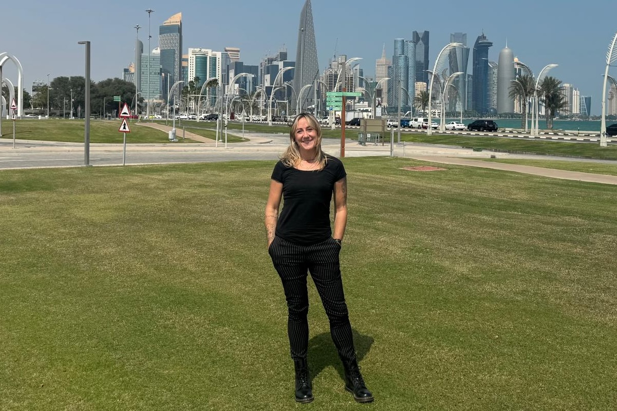 A woman standing in an open space in Doha, Qatar with the skyline in the background.