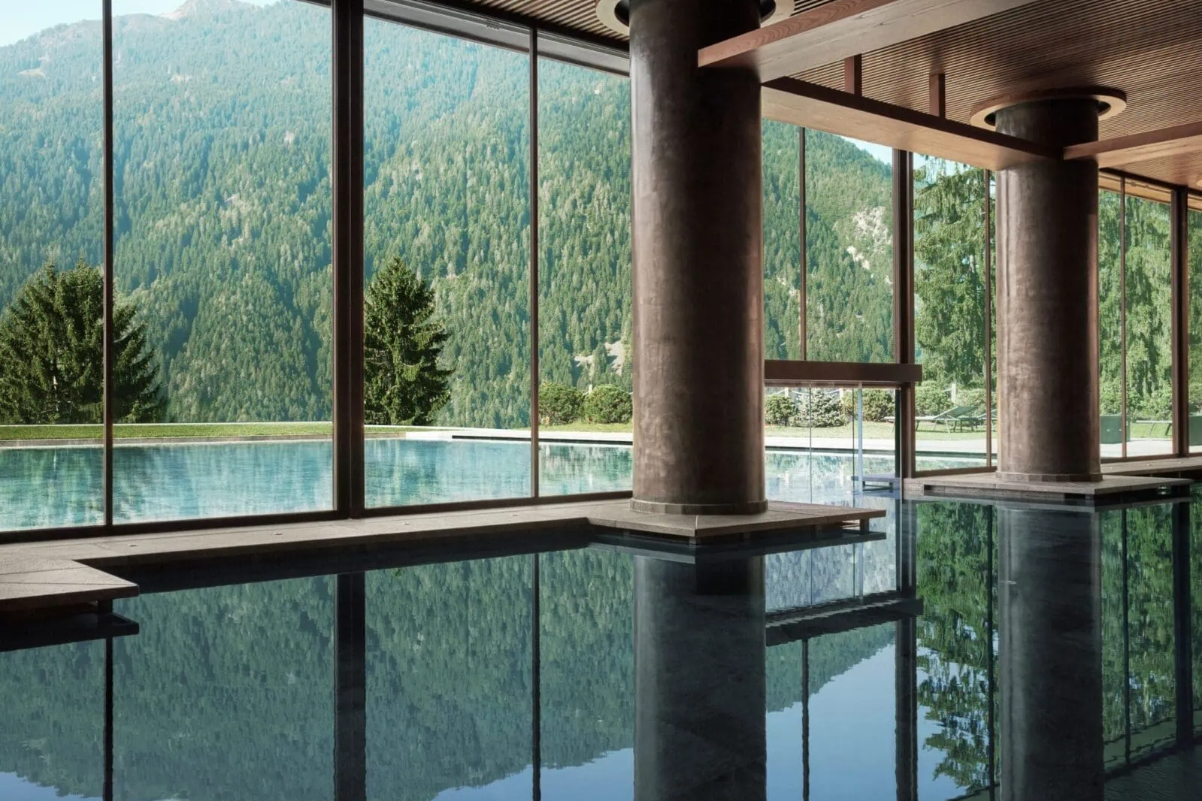 image of a pool at a spa in the Dolomites of Italy with natural light coming through big plate glass windows to a calm swimming pool