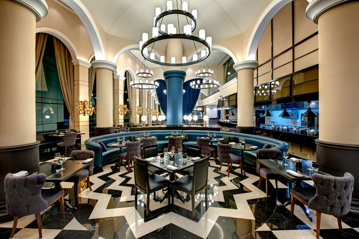 A fancy restaurant in Dubai with geometric tiled pattern floors and dramatic chandeliers in an Arabic style.