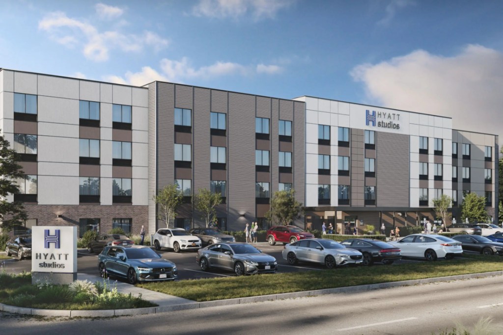 Image of the exterior of a Hyatt Studios extended stay brand in Mechanicsburg, Pennsylvania, on the outside on a sunny day, with cars in the parking lot and a new building.