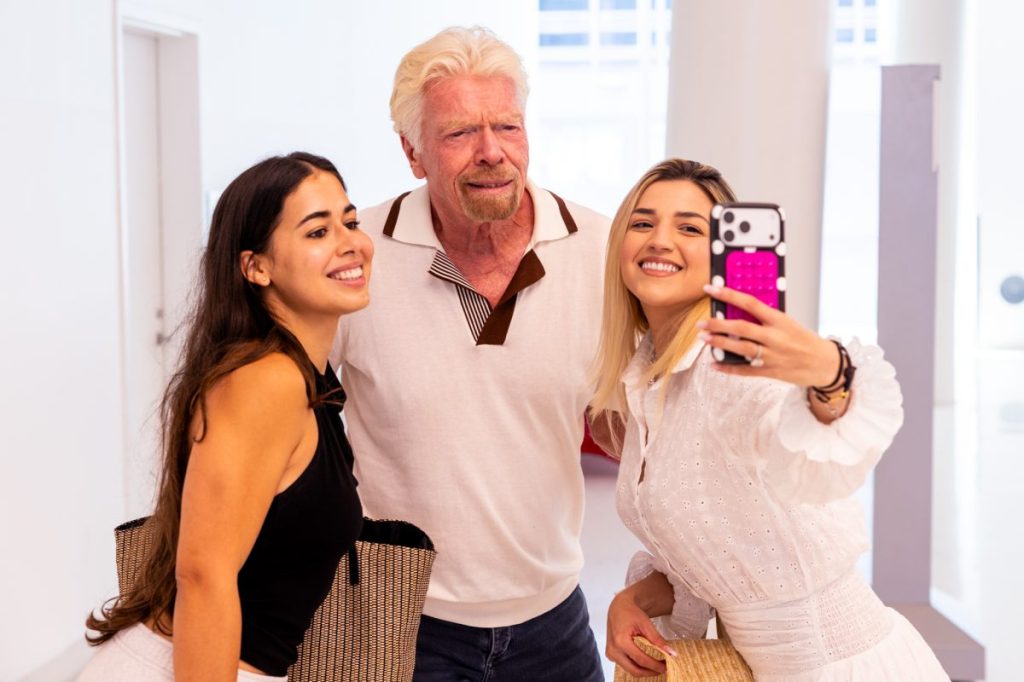 Richard Branson, founder of Virgin Group, poses for a selfie with two content creators.