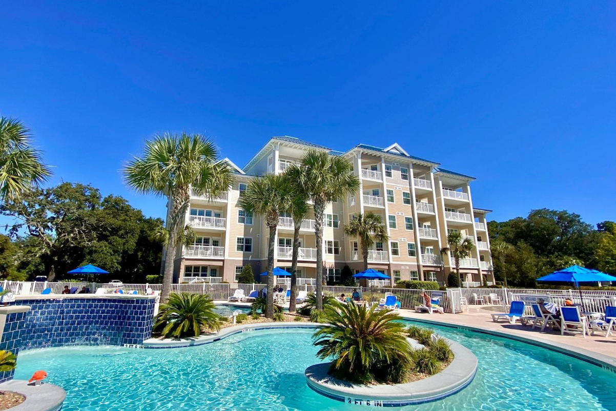 exterior image of a pretty timeshare resort in Hilton Head on a sunny day with a water feature in front